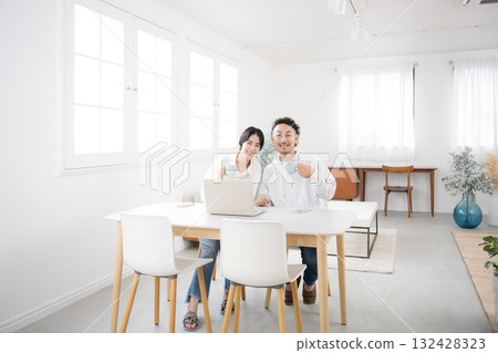 A couple looking at the camera in a beautiful living room. A wide-angle shot of a happy marriage. A couple looking at the camera in a beautiful living room. A wide-angle shot of a happy marriage. 132428323