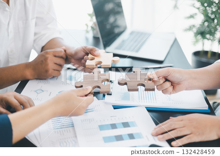 Business teamwork concept with people holding wooden puzzle pieces together, symbol of collaboration, strategy, problem solving, partnership and corporate success in modern office. business teamwork. Business teamwork concept with people holding wooden puzzle pieces together, symbol of collaboration, strategy, problem solving, partnership and corporate success in modern office. business teamwork. 132428459