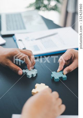 Business teamwork concept with people holding wooden puzzle pieces together, symbol of collaboration, strategy, problem solving, partnership and corporate success in modern office. business teamwork. Business teamwork concept with people holding wooden puzzle pieces together, symbol of collaboration, strategy, problem solving, partnership and corporate success in modern office. business teamwork. 132428460