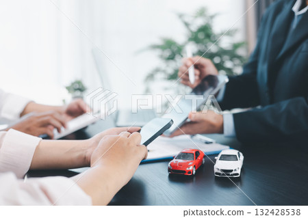 Car loan officer explaining contract details to customer with cash, calculator, key and toy car on table, concept of auto finance, leasing, insurance, payment plan and business agreement. car loan. Car loan officer explaining contract details to customer with cash, calculator, key and toy car on table, concept of auto finance, leasing, insurance, payment plan and business agreement. car loan. 132428538