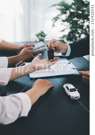 Customer receiving car key from dealer after signing contract, successful auto purchase and finance agreement at office desk, concept of vehicle loan, leasing, insurance or ownership. vehicle loan. Customer receiving car key from dealer after signing contract, successful auto purchase and finance agreement at office desk, concept of vehicle loan, leasing, insurance or ownership. vehicle loan. 132428541