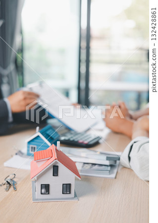 House model on desk with blurred people discussing contract in background, concept of real estate investment, mortgage loan, home ownership, property business and financial agreement. House model on desk with blurred people discussing contract in background, concept of real estate investment, mortgage loan, home ownership, property business and financial agreement. 132428861