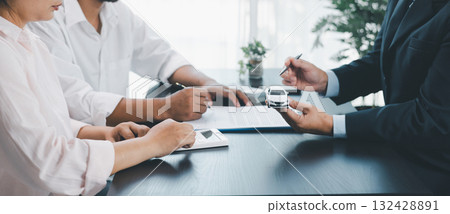 Panorama view of car loan agreement signing with dealer presenting vehicle model, customer using calculator at office desk, concept of auto finance, leasing, insurance and business contract. Panorama view of car loan agreement signing with dealer presenting vehicle model, customer using calculator at office desk, concept of auto finance, leasing, insurance and business contract. 132428891