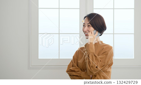 Woman making a phone call by the window 132429729