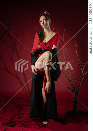 Woman poses in traditional Japanese dress against a red backdrop in a studio setting 132430689