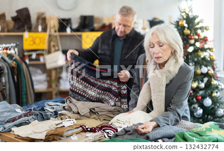 Elderly married couple choose sweater for the winter season together in fashionable clothing store. Elderly married couple choose sweater for the winter season together in fashionable clothing store. 132432774
