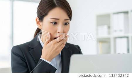 一名日本女員工對電腦螢幕感到驚訝 一名日本女員工對電腦螢幕感到驚訝 132432842