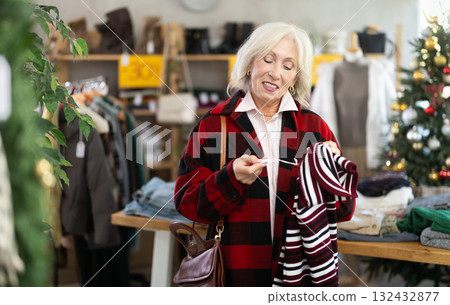 Positive mature woman choosing sweater in clothing store Positive mature woman choosing sweater in clothing store 132432877