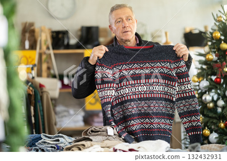 Attentive mature man choosing sweater in clothing store Attentive mature man choosing sweater in clothing store 132432931