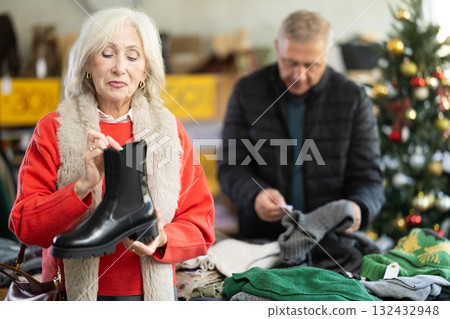 Happy elderly woman chooses fashionable platform boots in shoe store Happy elderly woman chooses fashionable platform boots in shoe store 132432948