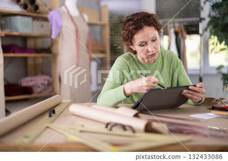 Female dressmaker working on digital sketch of dress in workshop Female dressmaker working on digital sketch of dress in workshop 132433086