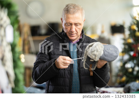 Mature man choosing a fur hat in the store 132433385