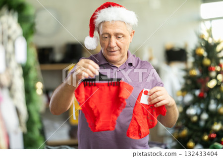 Mature male shopper selects red ladies panties as a Christmas gift in in fashionable clothing boutique Mature male shopper selects red ladies panties as a Christmas gift in in fashionable clothing boutique 132433404