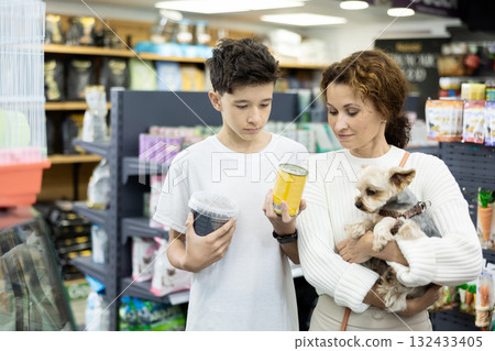 Woman with teenage son choosing food for Yorkshire terrier in pet store Woman with teenage son choosing food for Yorkshire terrier in pet store 132433405