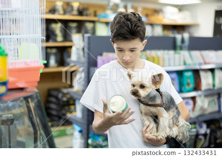 Focused preteen boy choosing canned dog food for Yorkie in pet store Focused preteen boy choosing canned dog food for Yorkie in pet store 132433431