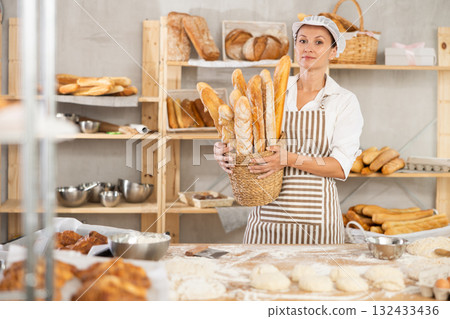 Female baker with basket of fresh baguettes Female baker with basket of fresh baguettes 132433436
