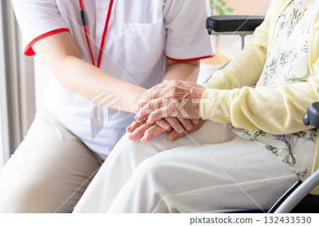 護理人員握著輪椅上一位女士的手 132433530