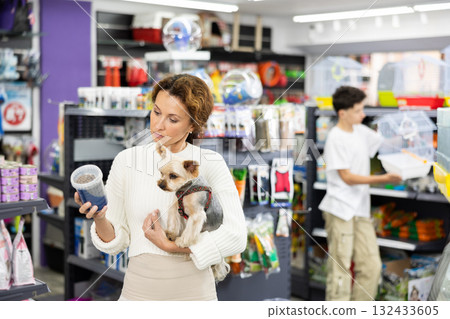 Buyers woman with Yorkshire Terrier choose healthy food and nutrition for pet in tin can 132433605