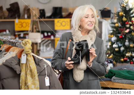 Mature woman choosing heeled boots in Christmas shop Mature woman choosing heeled boots in Christmas shop 132433648
