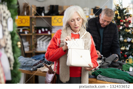Mature woman chooses fashionable handbag in clothing boutique 132433652