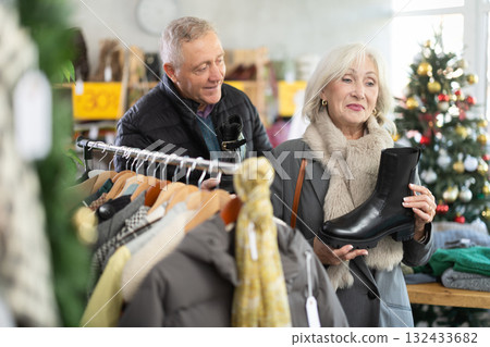 Elderly couple choosing platform boots on Christmas tree background 132433682