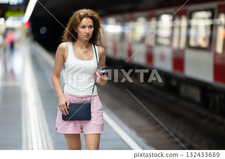 Woman waiting for subway train at an underground station 132433689