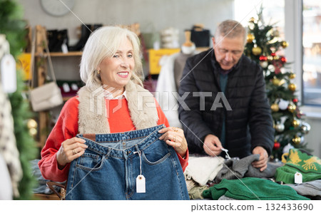 Glad mature woman choosing jeans pantaloons in clothing store 132433690