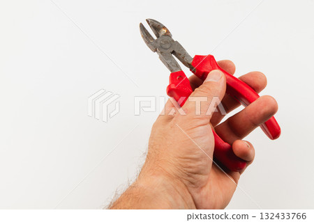 Hand holding red-handled wire cutters for DIY projects 132433766