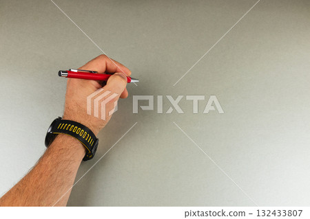 Person holding a red pen over a blank surface ready to write 132433807