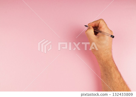 Hand holding pen on pink background ready to draw or write 132433809