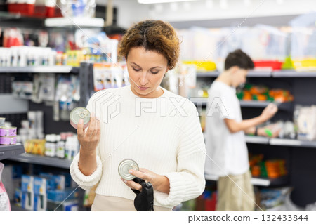 Female shopper selecting canned dog food for Yorkie in pet store Female shopper selecting canned dog food for Yorkie in pet store 132433844