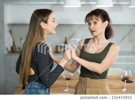 At home two women get going in pair dance in kitchen 132433852