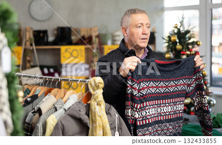 Attentive mature man choosing sweater in clothing store Attentive mature man choosing sweater in clothing store 132433855