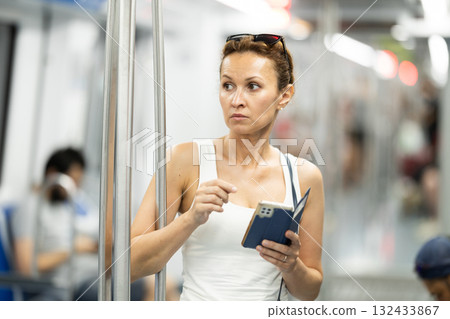 Portrait of female passenger using tablet in subway car 132433867