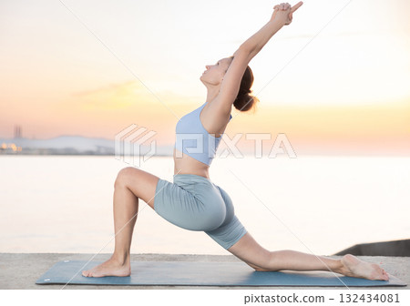 Near sea during sunset, girl performs variations of virabhadrasana Near sea during sunset, girl performs variations of virabhadrasana 132434081
