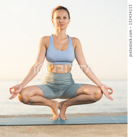 Near sea during sunset, girl performs prapadasana Near sea during sunset, girl performs prapadasana 132434115