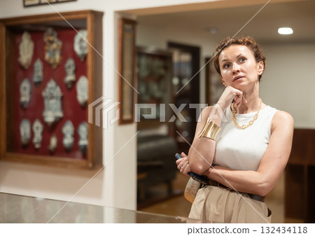 Thoughtful woman examining historacal exhibits in museum 132434118