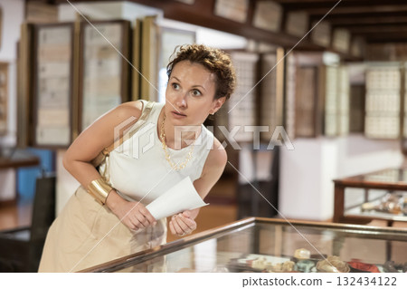 Woman with sheet piece of paper in her hands walks around museum hall 132434122