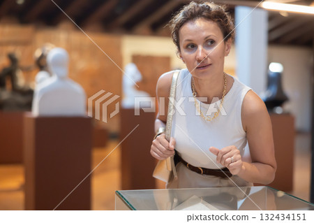 Woman looking at exhibits in glazed stands in museum Woman looking at exhibits in glazed stands in museum 132434151