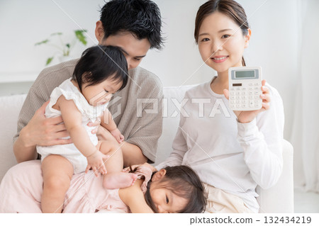 Parent and daughter, family of four, calculator, smiling Parent and daughter, family of four, calculator, smiling 132434219