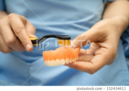 Asian senior woman patient clean teeth denture with toothbrush for chew food. 132434611