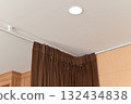 Modern home interior design detail with brown curtain hanging from ceiling track. recessed light illuminates cozy window decoration for calm and stylish living space 132434838