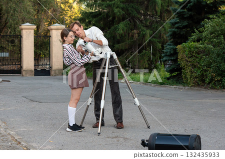 Man and girl adjusting telescope mount outdoors 132435933
