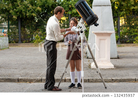 Teacher explains telescope component while student listens attentively Teacher explains telescope component while student listens attentively 132435937