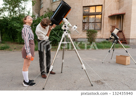 Man observes sky using telescope during astronomy session 132435940