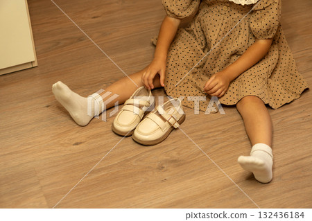 Young girl in polka dot dress holding beige shoes 132436184