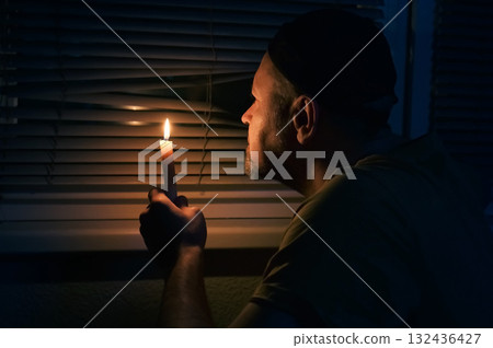 Blackout, No electricity. No electricity. A man with a candle in the dark waits for the power to come back on. 132436427