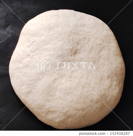 Round raw bread dough on a dark background. Round raw bread dough on a dark background. 132438287