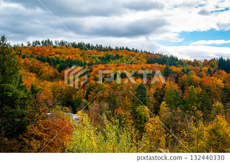 Autumn countryside near Luhacovice, Czech Republic, with colorful forests, meadows, and gentle hills in shades of red, orange, and yellow at the beginning of fall. Autumn countryside near Luhacovice, Czech Republic, with colorful forests, meadows, and gentle hills in shades of red, orange, and yellow at the beginning of fall. 132440330