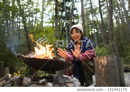 A woman making a bonfire at a campsite A woman making a bonfire at a campsite 132441179